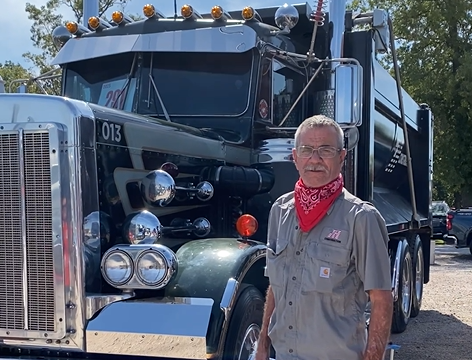 Truck owner standing in front of a black dump truck