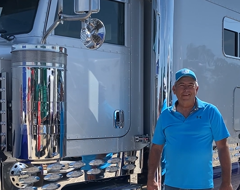 Truck owner standing beside a silver semi truck