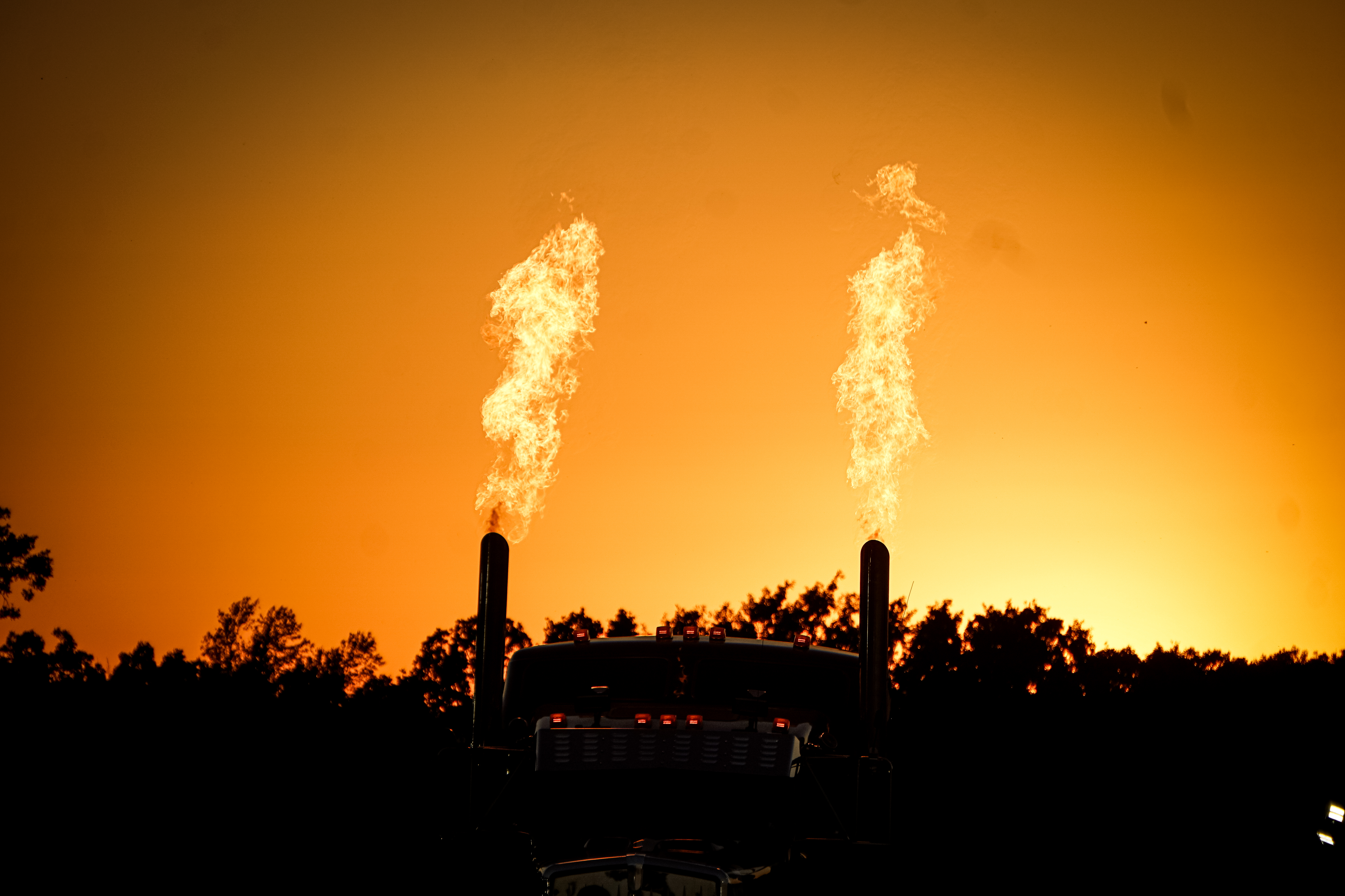 semi truck flames spouting from exhaust stacks at dusk